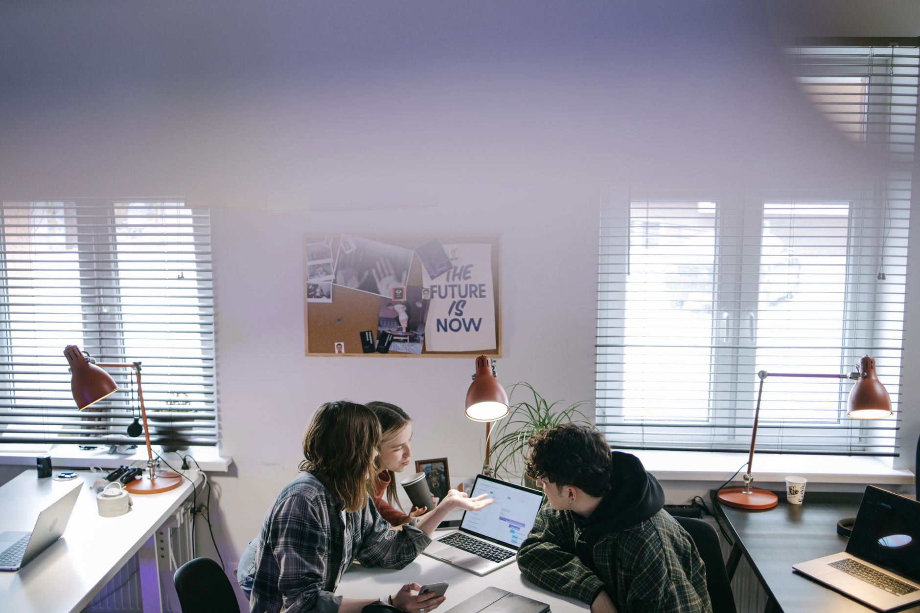 A group of people discussing ideas around laptops in a bright, modern office space — illustrating: MSP vs Traditional IT Support in Central Florida: Which Setup Protects Your Small Business Best?